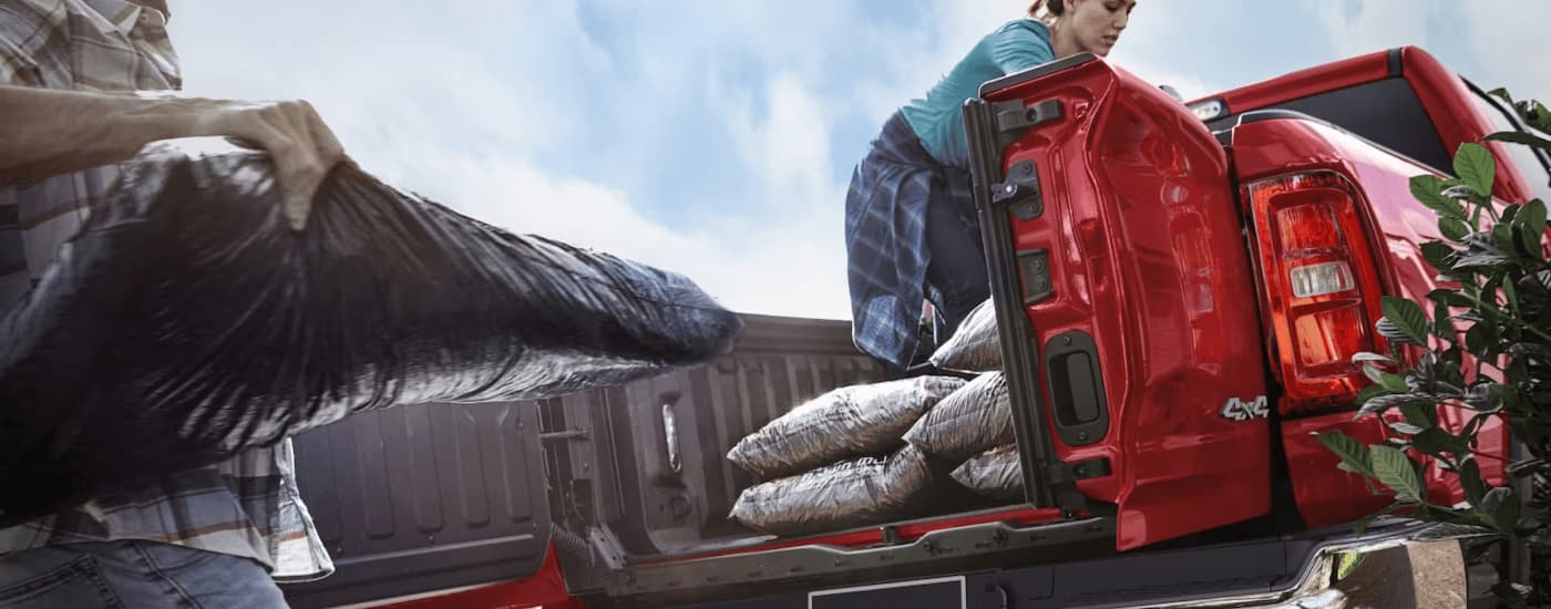 Bags being loaded into the bed of a red 2025 Ram 1500 Big Horn