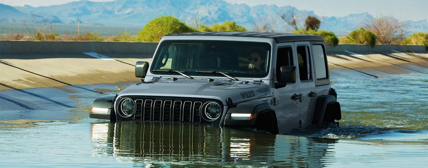 Grey 2026 Jeep Wrangler driving in a river.