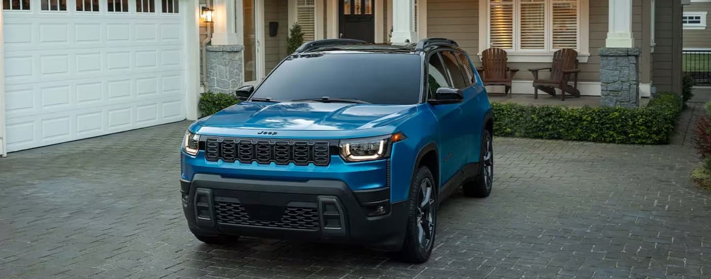 A blue 2026 Jeep Cherokee parked in a driveway