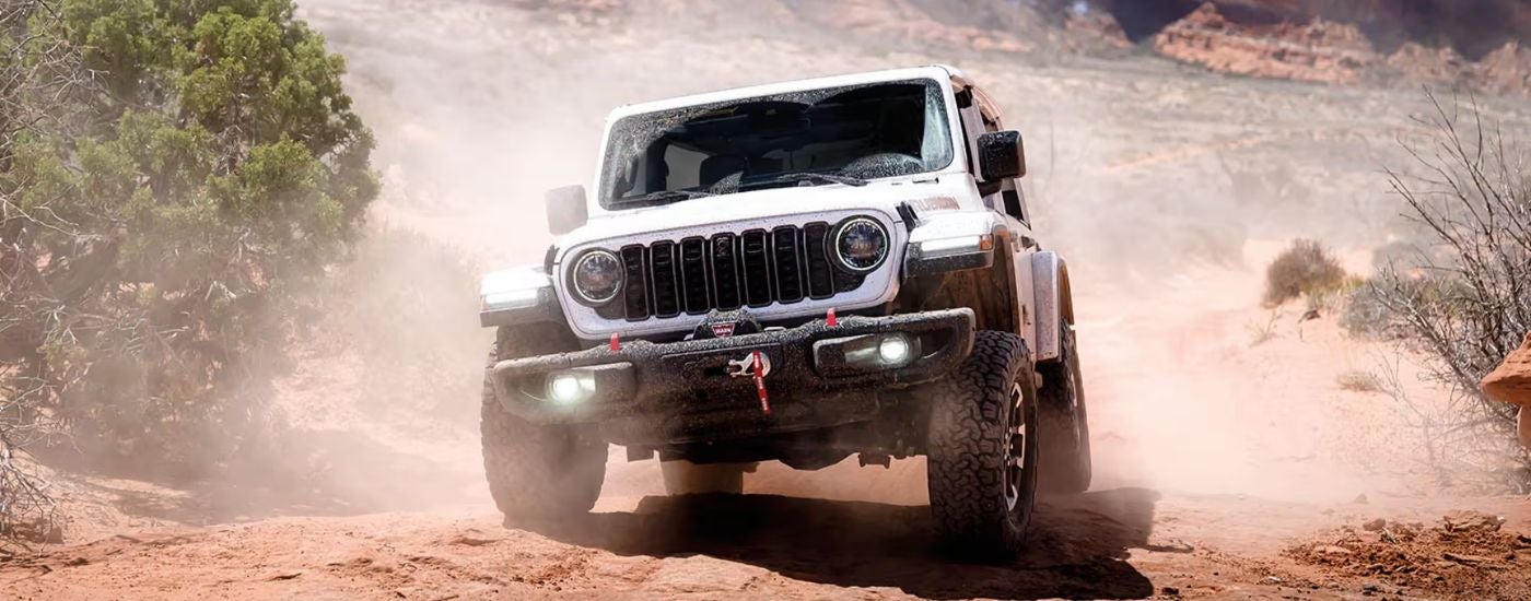 White 2026 Jeep Wrangler driving off-road.