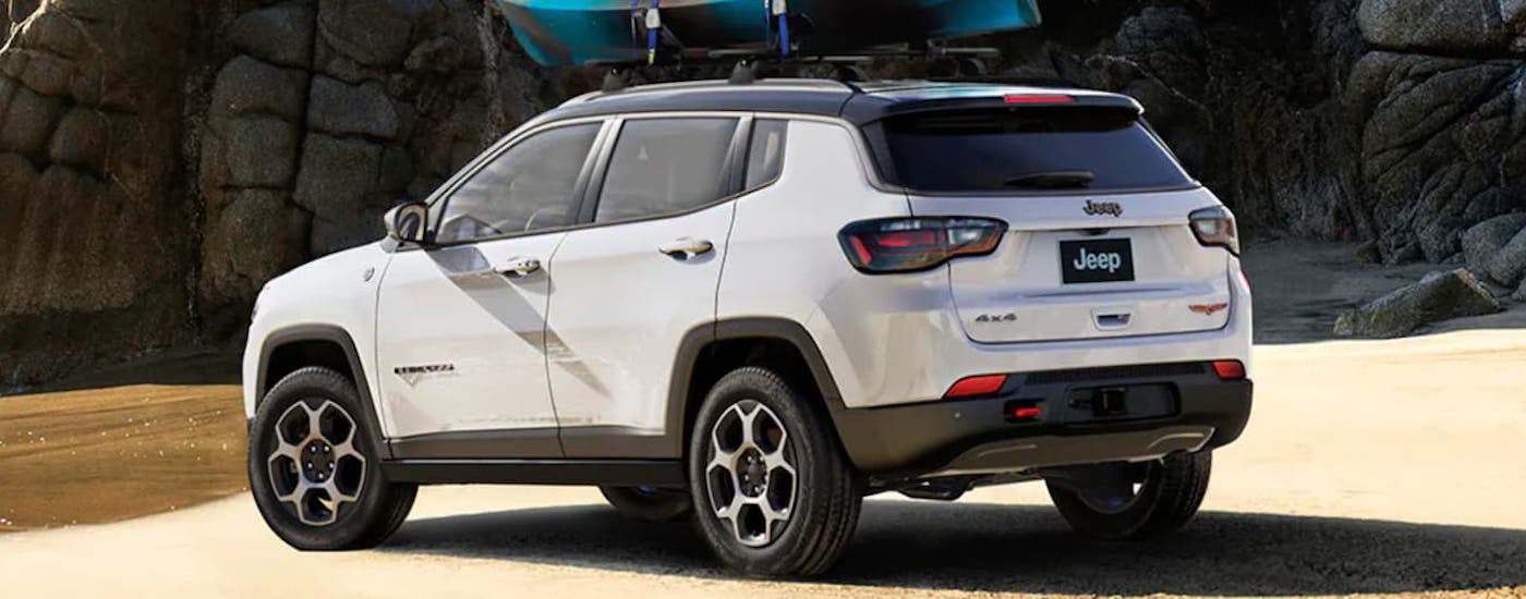 Rear of a white 2025 Jeep Compass parked near a lake.