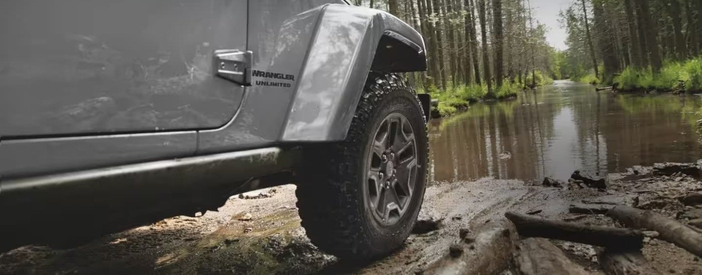 A grey 2017 Jeep Wrangler Unlimited off-road near a mud puddle.