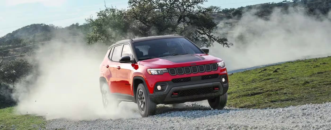 A red 2026 Jeep Compass driving on a dirt path after visiting a Jeep dealer near Wixom.