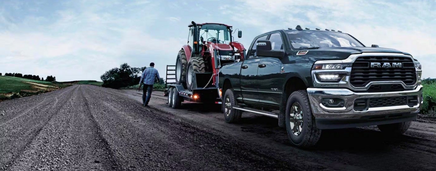 Black 2025 Ram 2500 towing a tractor