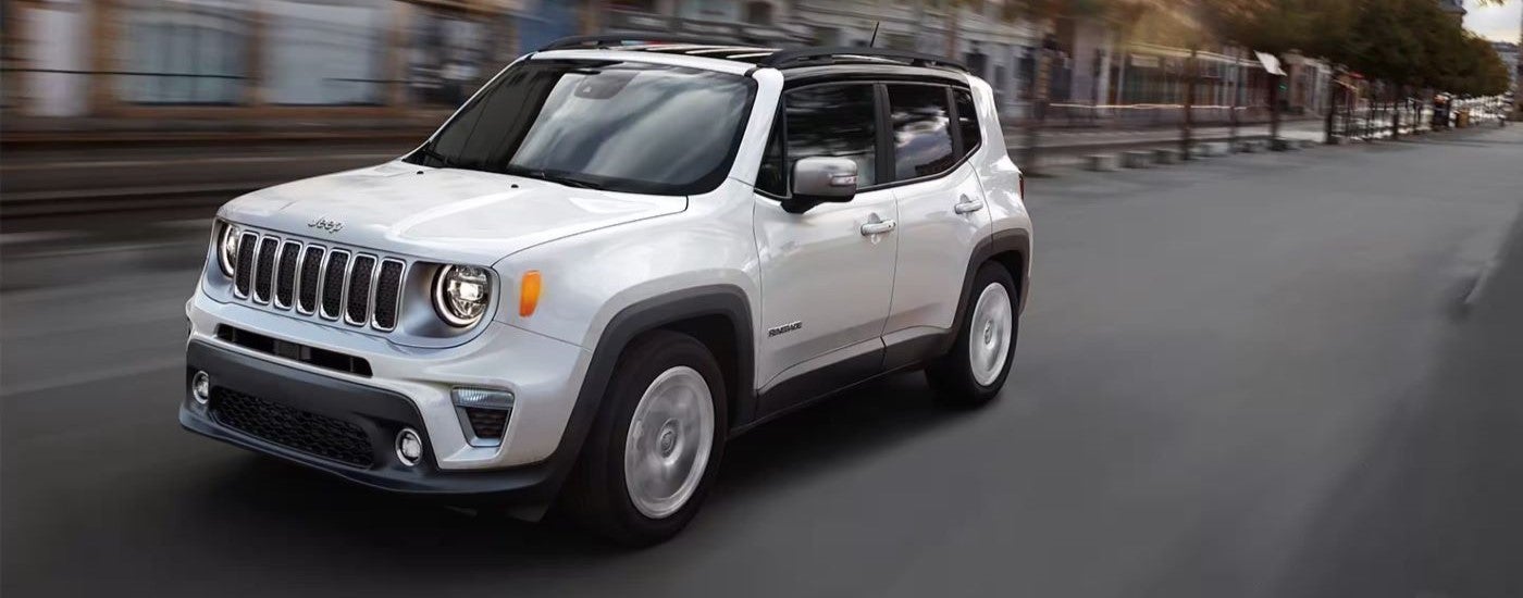 White 2020 Jeep Renegade driving down a city street.
